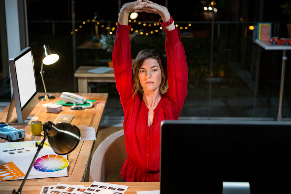 Businesswoman stretching hands at her desk in office