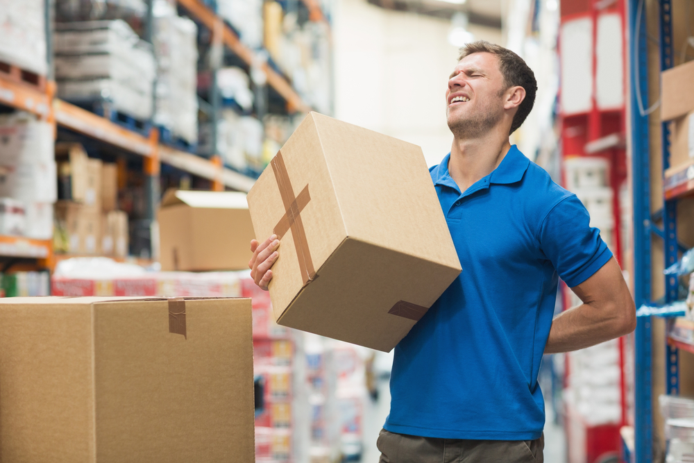 Side view of worker with backache while lifting box in the warehouse-1